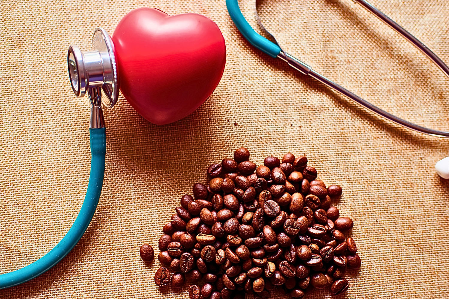 Stethoscope on a fake heart next to coffee beans